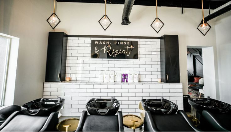 the interior of a hair salon with black and white chairs