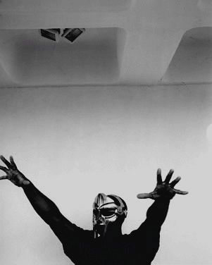 black and white photograph of a man with his arms in the air wearing a mask