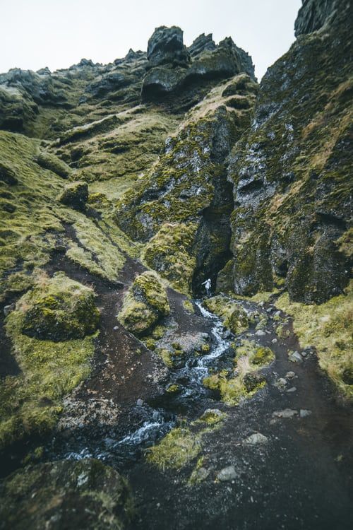 mossy rocks and water in the middle of a mountain range with small stream running between them