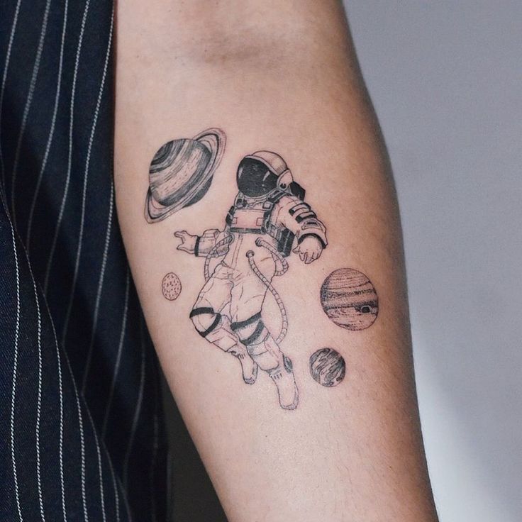 a man's arm with an astronaut tattoo on it and planets in the background