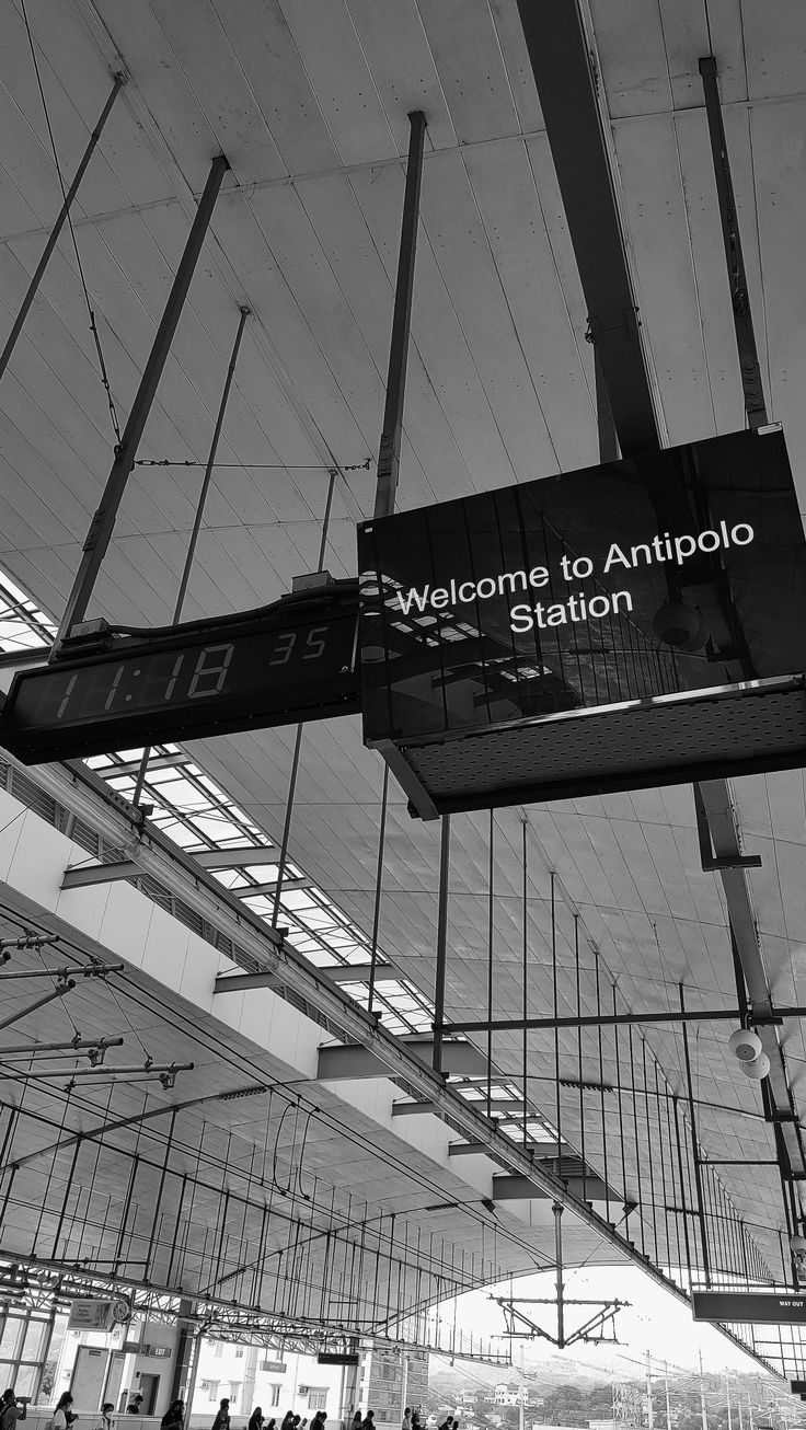 a black and white photo of people waiting in line at an airport with the sign saying, welcome to antepolo station