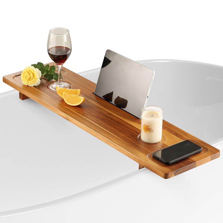 a laptop computer sitting on top of a wooden tray next to a glass of wine