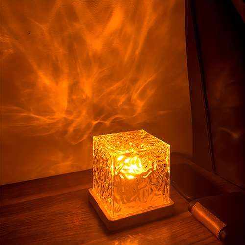 a lit candle sitting on top of a wooden table next to a glass block with flames in it