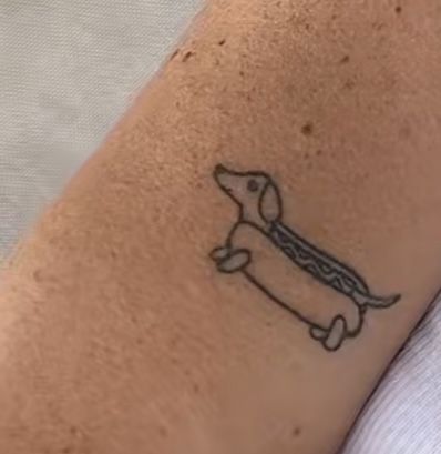 a small tattoo on the arm of a person with a dog in it's collar