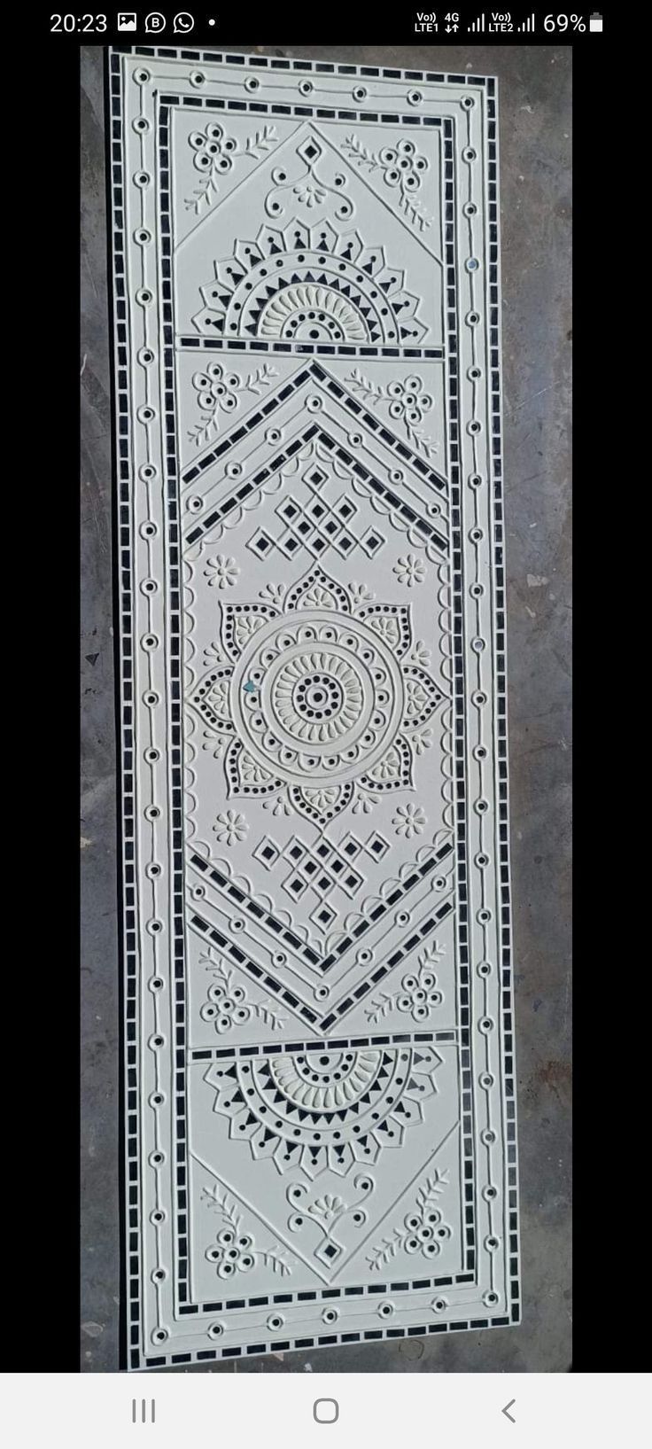 a white and black rug with an intricate design on the bottom, in front of a gray background