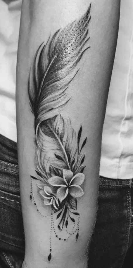 a black and white photo of a feather with flowers on it's side arm