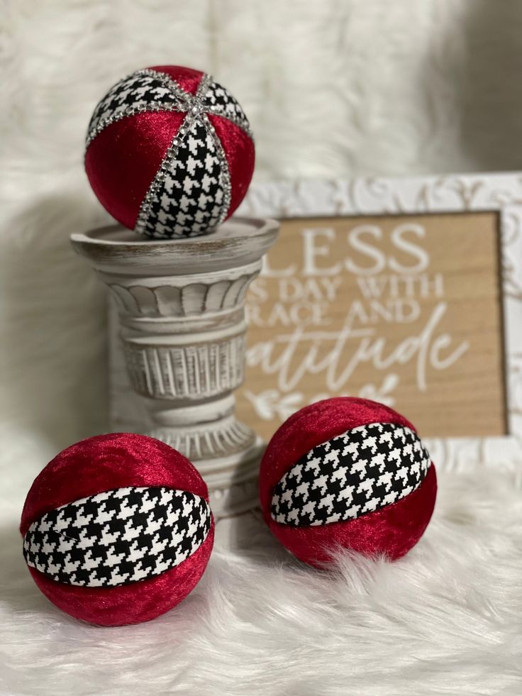 two red balls with black and white designs on them sitting next to a vase filled with flowers