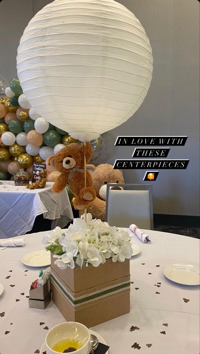 a teddy bear sitting on top of a table next to a box filled with flowers