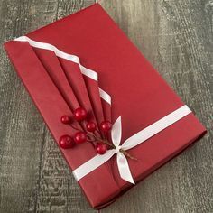 a red wrapped gift with white ribbon and berries