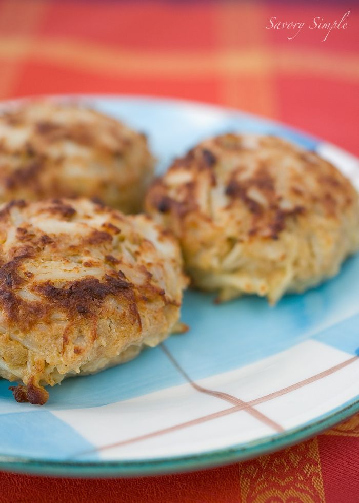 three crab cakes sitting on top of a blue and white plate