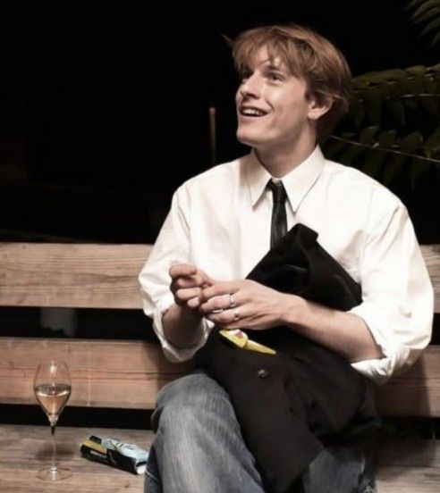 a man sitting on a bench next to a glass of wine