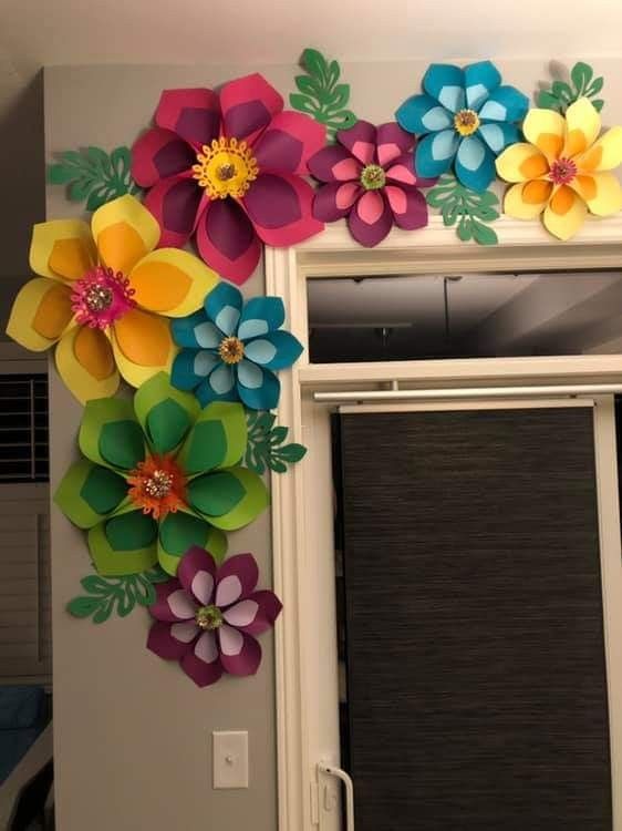 colorful paper flowers are hanging on the wall