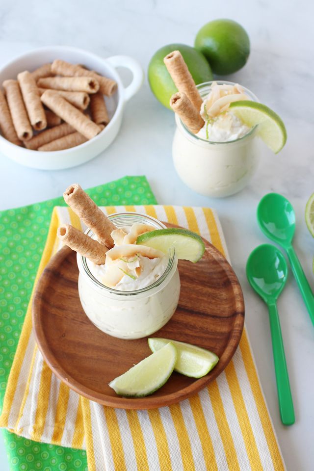 two small jars filled with food on top of a wooden plate next to spoons