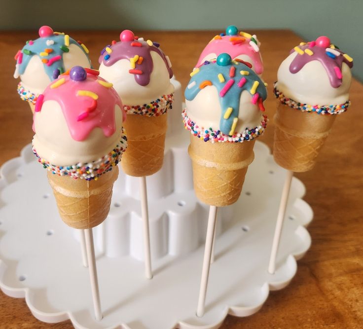 four ice cream cones with sprinkles on them sitting on a white tray