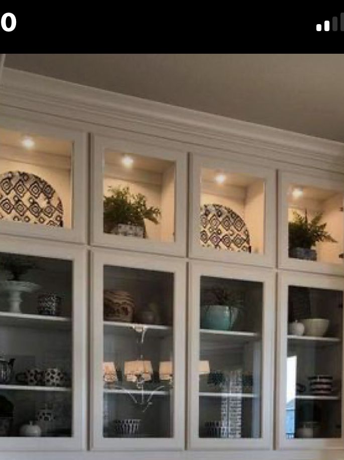 a kitchen with white cabinets and glass doors