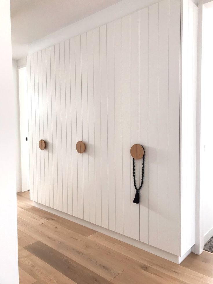 an empty room with white walls and wooden flooring, two hooks on the wall