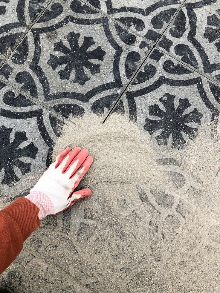 a person with white gloves on their hands standing in front of a black and white tile floor