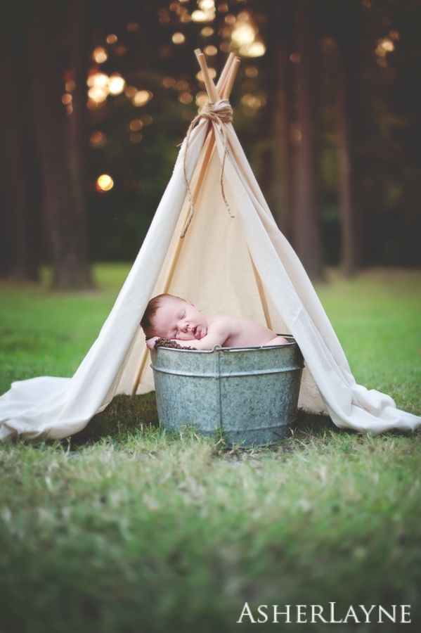 a baby sleeping in a bucket with a teepee