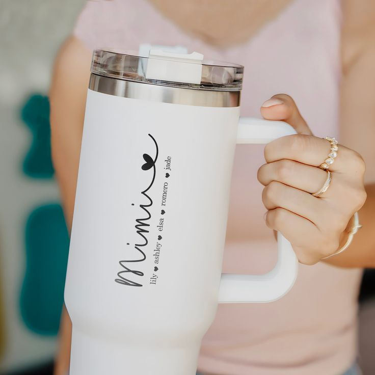 a woman holding a white coffee cup in her hand