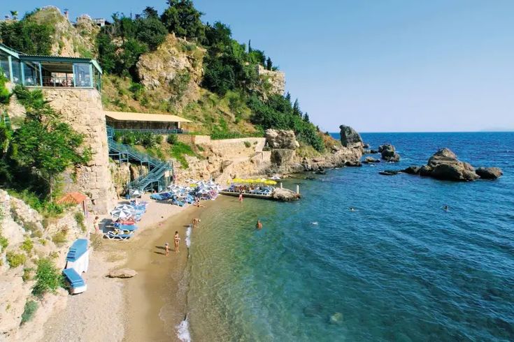 the beach is crowded with people and umbrellas near the water's edge,