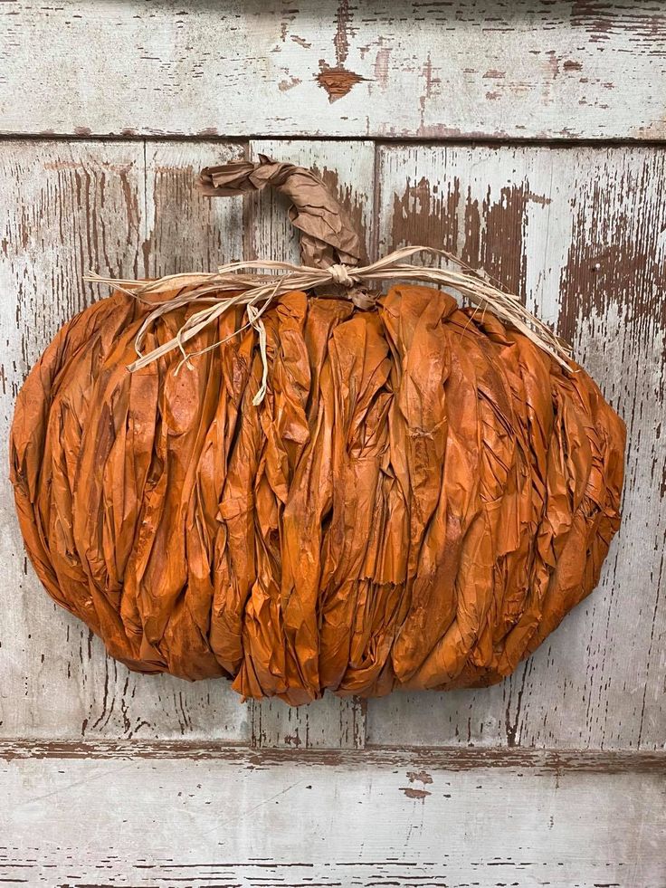 an orange pumpkin sitting on top of a white wooden wall next to a brown string