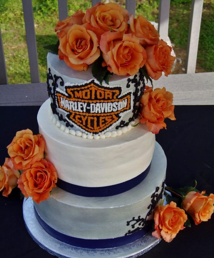 a three tiered cake with orange roses on the top and harley davidson logo on the side