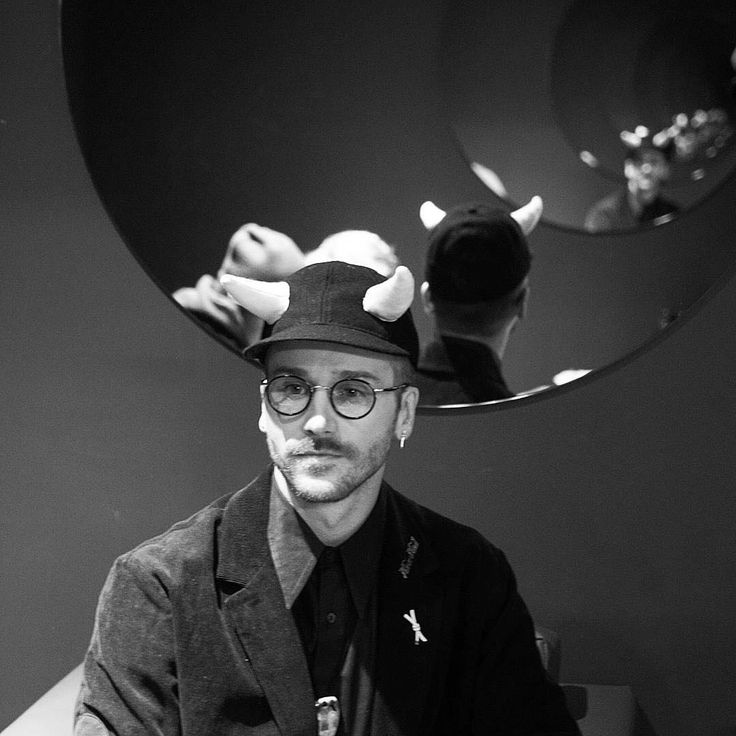 a man sitting in front of a mirror wearing glasses and a hat with horns on his head