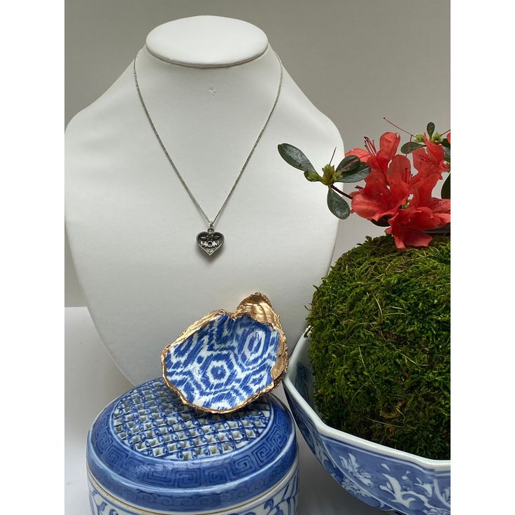 Our special Mother's Day gift includes both a Mother's Day necklace PLUS our signature blue and white ikat design oyster shell jewelry dish. Both of these are hand-made in the Classic Legacy design studio. The oyster shell dish is made with a real oyster shell. Then the pattern is applied in a decoupage process, enameled, and the edges are hand gilded with gold leaf. The fine curb chain necklace is 16" long. The pewter heart says "Mom". This is a great gift to honor your Mom. Unique Shell Pendant Necklace For Gift, Unique Shell Pendant Necklace As Gift, Unique Pendant Shell Necklace As Gift, Elegant Blue Shell Necklace For Gift, Elegant Blue Shell Necklace As A Gift, Artisan Shell Pendant Necklace For Gift, Silver Round Shell Necklace For Gifts, Silver Shell-shaped Necklace For Gift, Blue Shell-shaped Jewelry For Gift