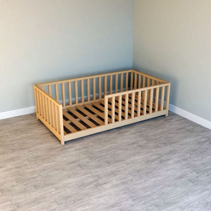 an empty room with a wooden crib on the floor and light blue walls behind it