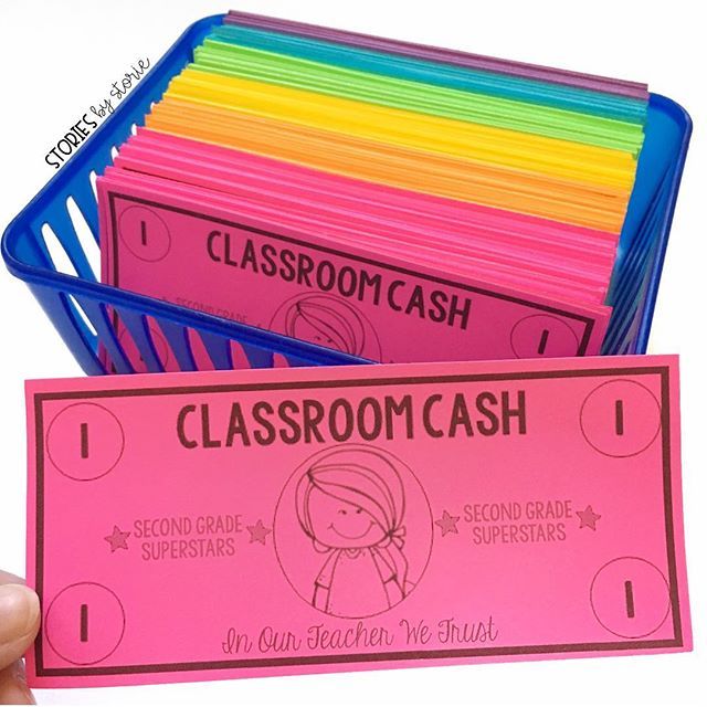 a person holding up a classroom cash card in front of a stack of colored papers