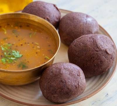 some food is on a plate and next to a bowl of soup with three balls