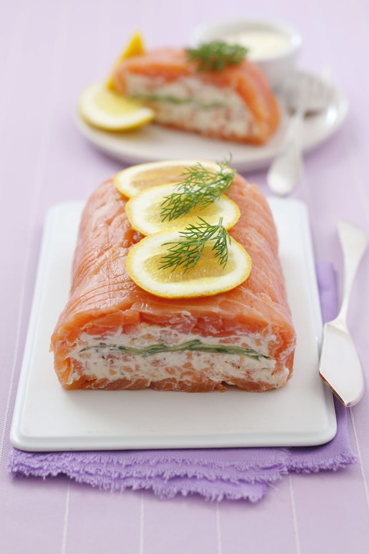 two slices of salmon on a plate with lemons and dill