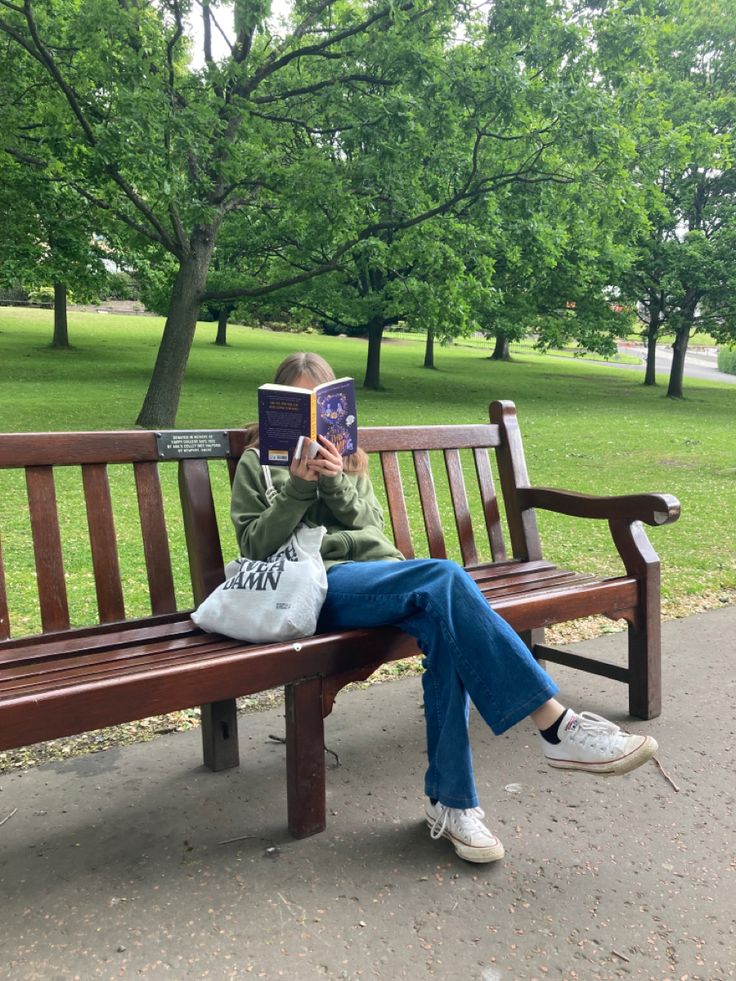 a woman sitting on a bench reading a book