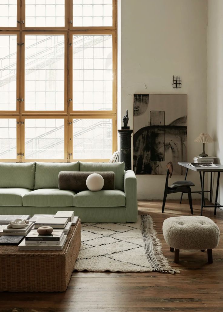 a living room filled with lots of furniture and large windows in the wall behind it