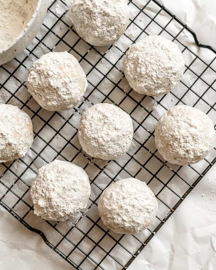 several balls of powdered sugar on a cooling rack