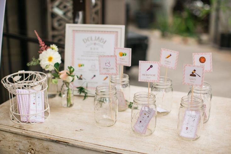 mason jars with place cards on them sitting on a table