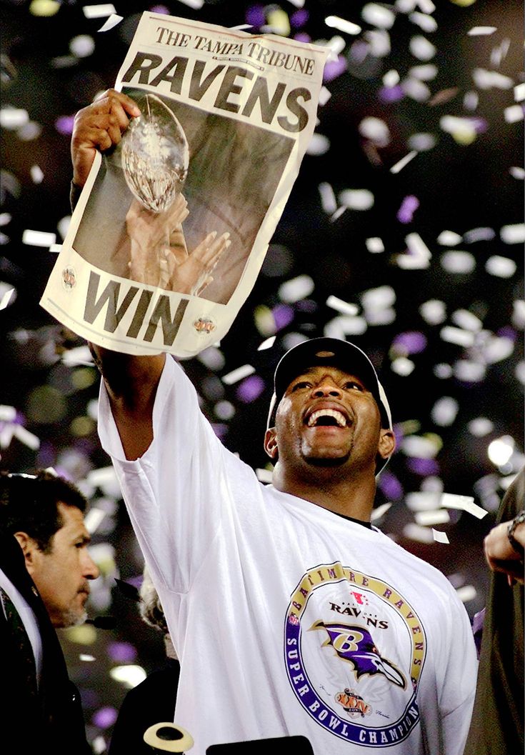 a man holding up a newspaper with confetti in front of him and the baltimore ravens logo on it