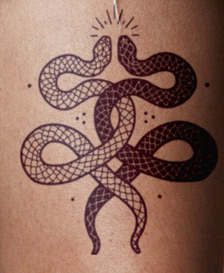 a tattoo on the back of a woman's thigh with an image of two snakes