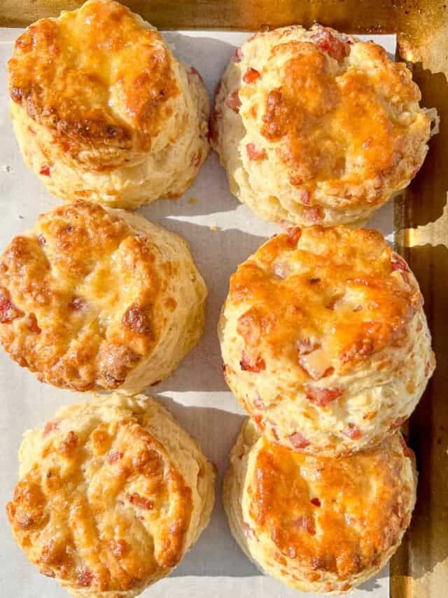 six biscuits with cheese and meat on top