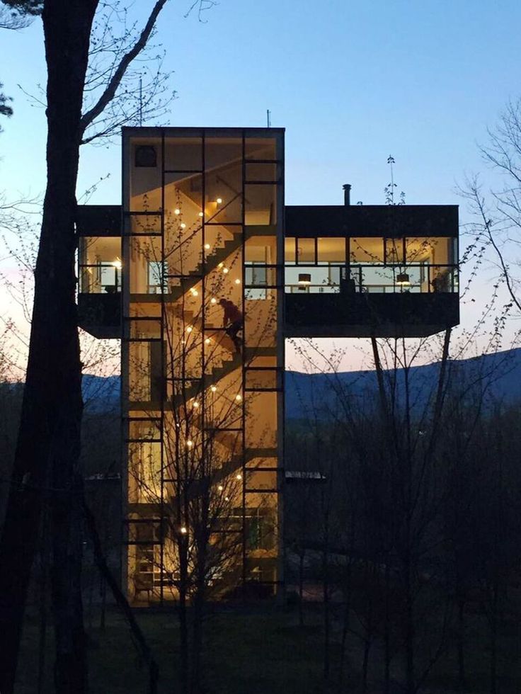 a tall glass building sitting next to a forest