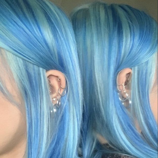 a woman with blue hair has ear piercings on her ears