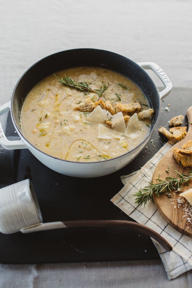 a bowl of soup with meat and cheese on the side, next to some bread