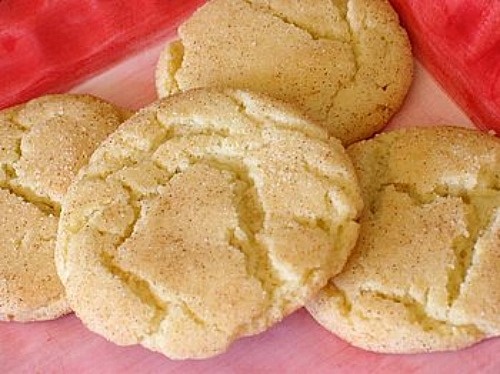 four cookies are on a pink plate next to a red cloth