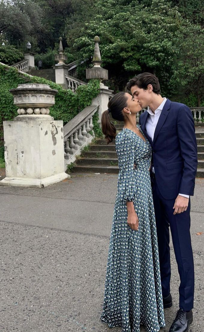 a man and woman kissing in front of some stairs