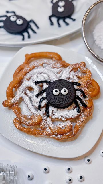 a plate topped with cookies covered in powdered sugar and a spider cookie on top of it