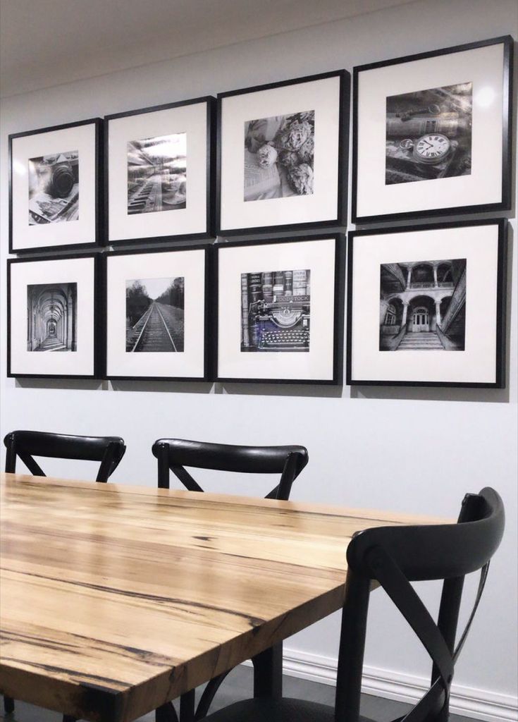 a dining room table with black chairs and pictures on the wall