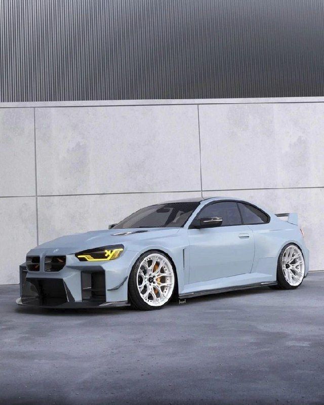 a light blue sports car parked in front of a gray wall with white rims