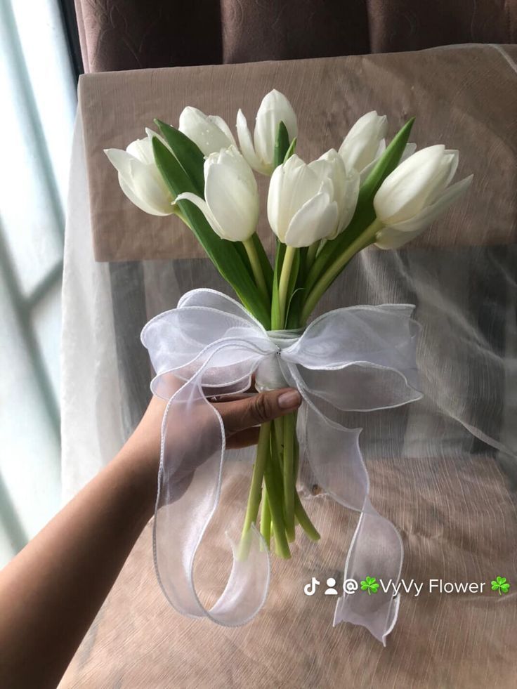 a bouquet of white tulips tied to a chair with a ribbon around it