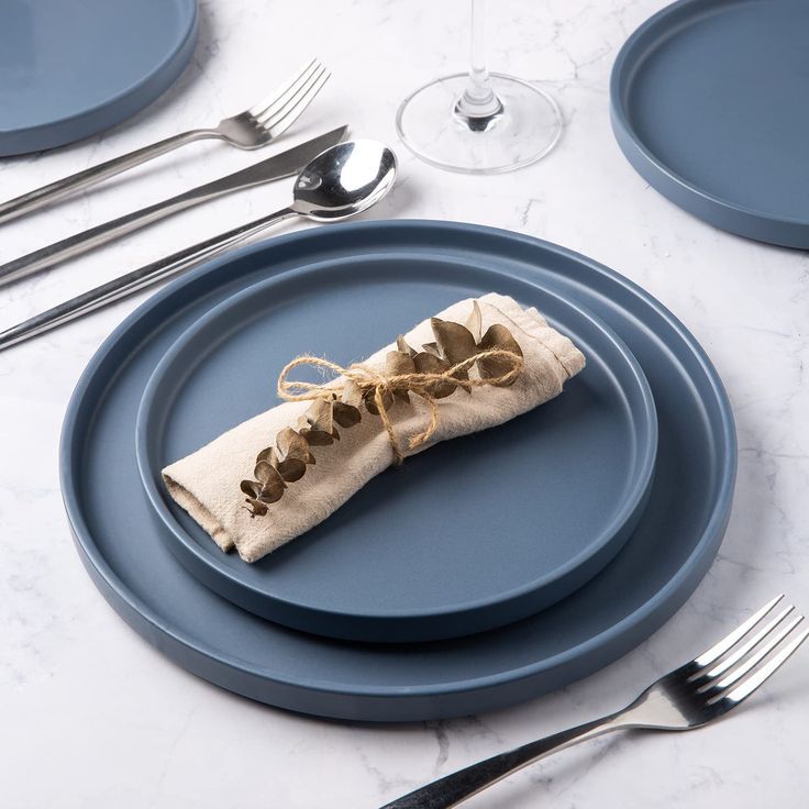 a napkin wrapped in twine on top of a blue plate with silverware and utensils