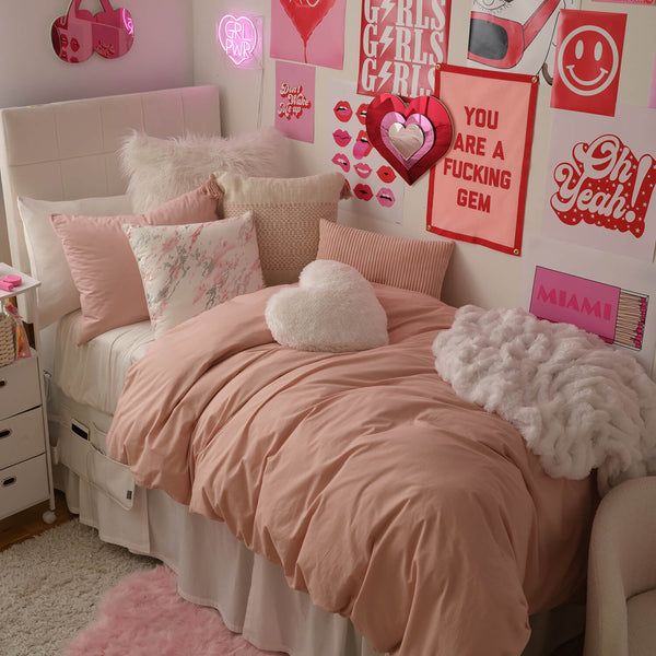 a bedroom decorated in pink and white with lots of pictures on the wall above the bed